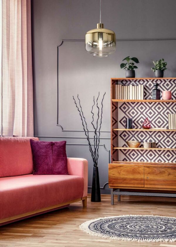 antique-wooden-bookcase-with-decorations-in-an-elegant-gray-living-room-interior-with-a-comfortable-powder-pink-sofa