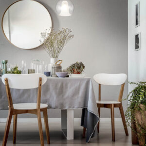 lamp-above-white-chairs-and-table-in-grey-dining-room-interior-with-plants-and-round-mirror-real-photo