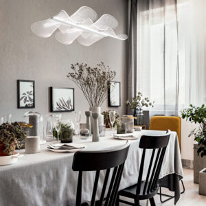 lamps-above-black-chairs-at-table-with-flowers-in-bright-dining-room-interior-with-posters-real-photo