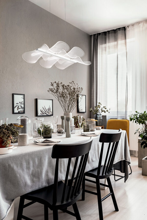 lamps-above-black-chairs-at-table-with-flowers-in-bright-dining-room-interior-with-posters-real-photo